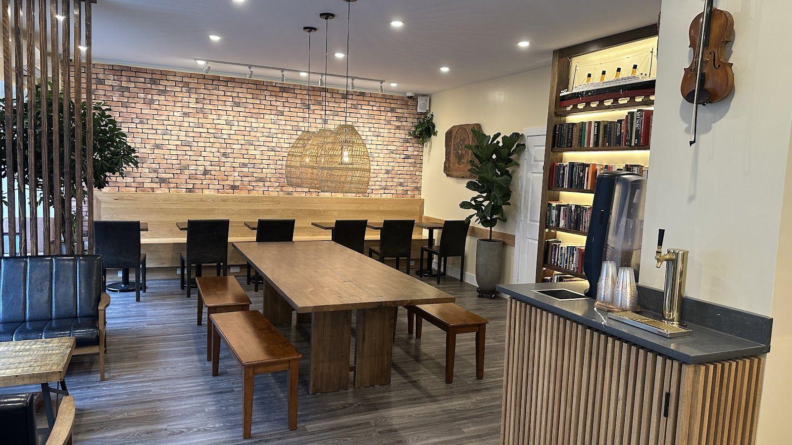 Inside the café: exposed brick, long wood benches, a lit bookshelf and a violin on the wall