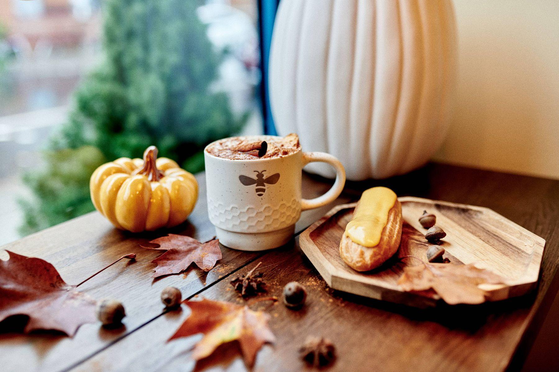 A honeycomb-embossed bee mug of spiced hot chocolate beside a honey éclair